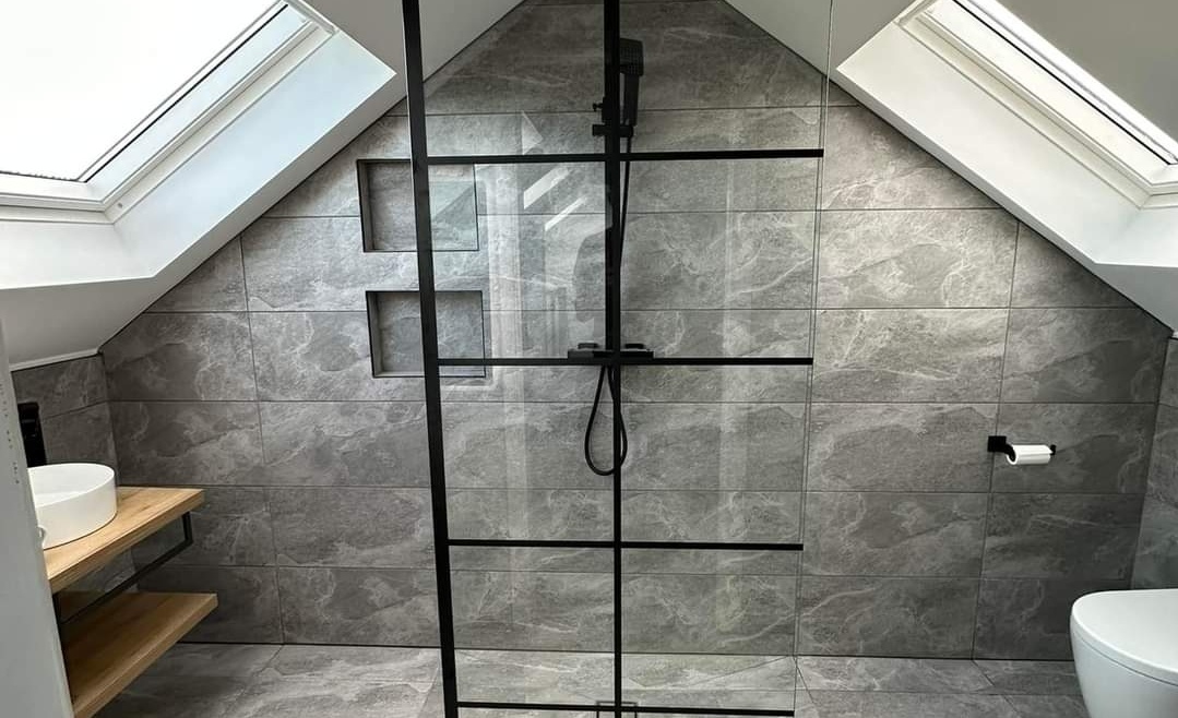 Modern attic bathroom with skylights, walk-in shower, and grey tiled walls designed by The Irish Attic Company.