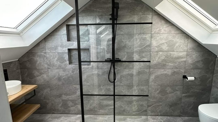 Modern attic bathroom with skylights, walk-in shower, and grey tiled walls designed by The Irish Attic Company.