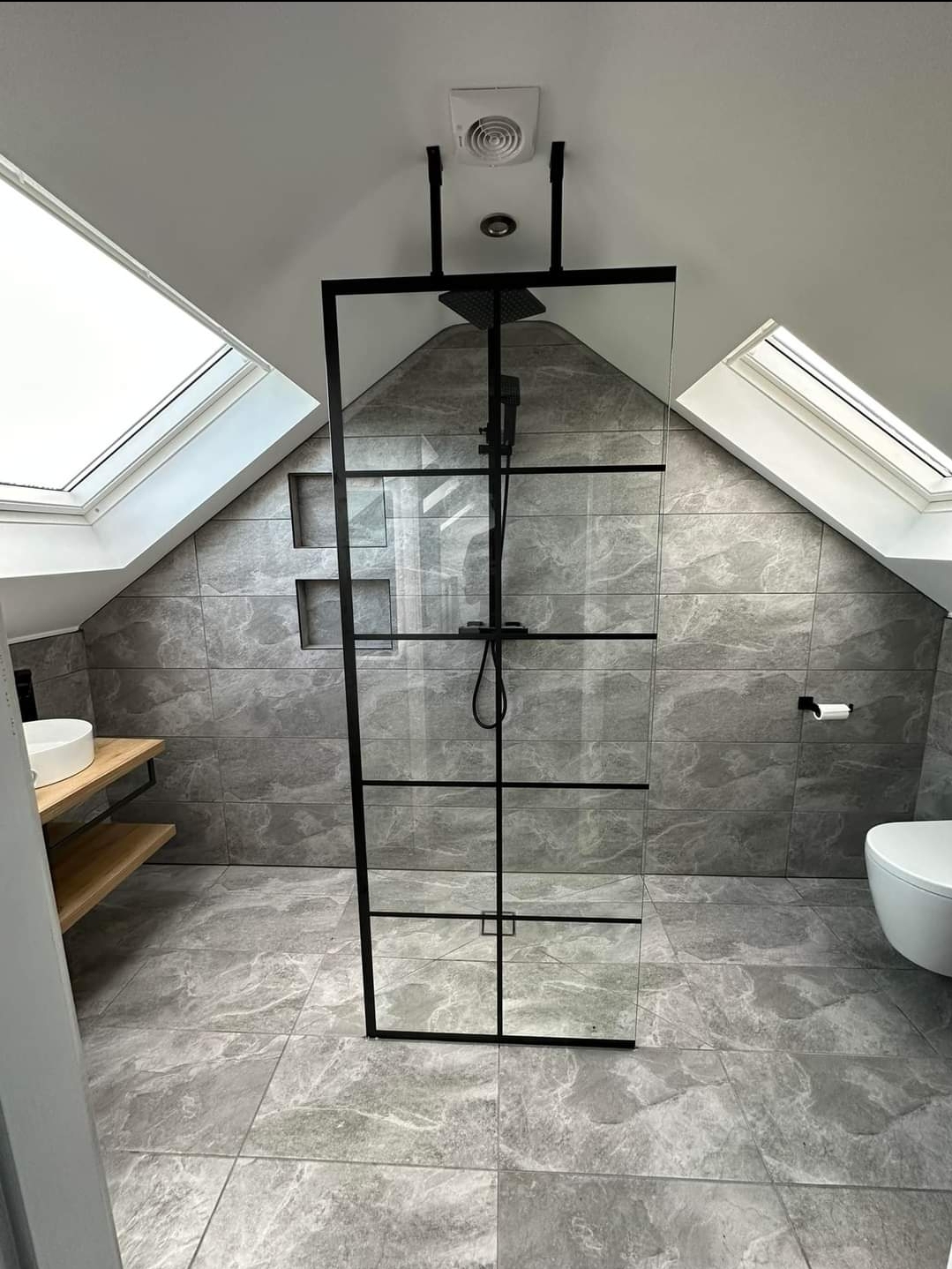 Modern attic bathroom with skylights, walk-in shower, and grey tiled walls designed by The Irish Attic Company.