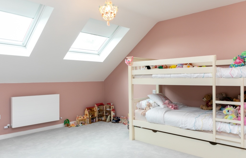 Finished attic room with skylights, blush pink walls, and children's artwork