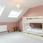 Finished attic room with skylights, blush pink walls, and children's artwork
