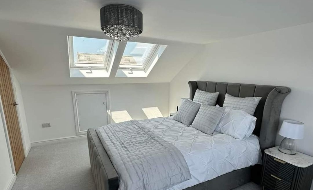 Finished attic bedroom with grey carpet and natural light from Velux windows, part of a Dublin home renovation by The Irish Attic Company.